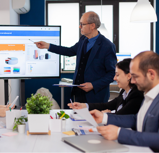 Business team in meeting as a presenter shows software dashboard on screen—promoting Movegistics' guide on choosing the right moving software.